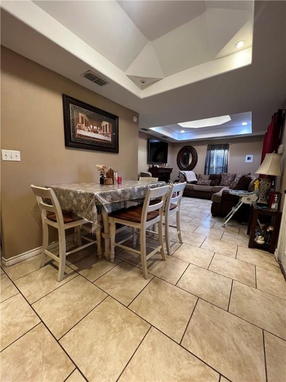 tiled dining space with a raised ceiling