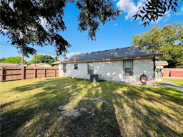 rear view of house featuring cooling unit and a yard