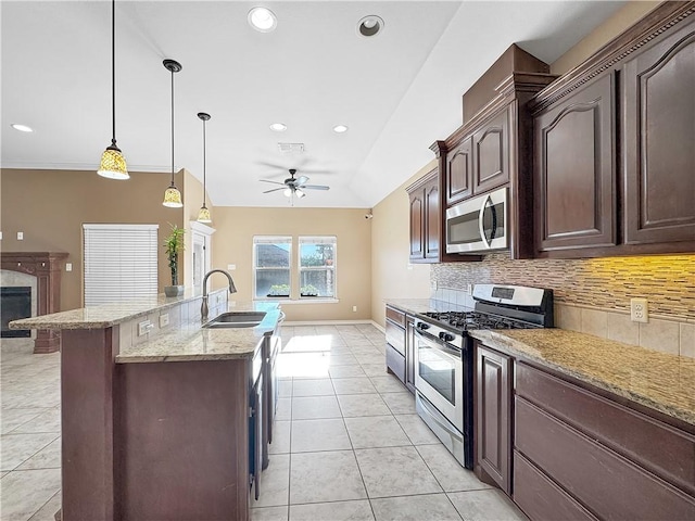 kitchen featuring appliances with stainless steel finishes, tasteful backsplash, light stone counters, sink, and hanging light fixtures