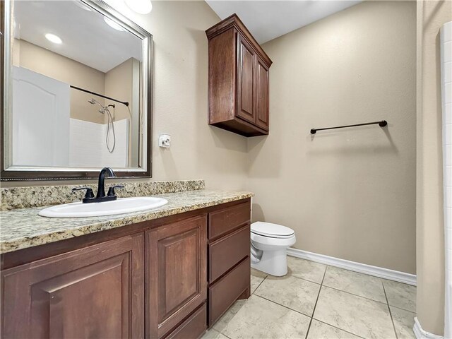 bathroom featuring tile patterned flooring, vanity, toilet, and walk in shower