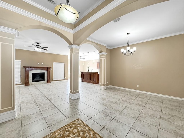 unfurnished living room with ceiling fan with notable chandelier, crown molding, a high end fireplace, and decorative columns