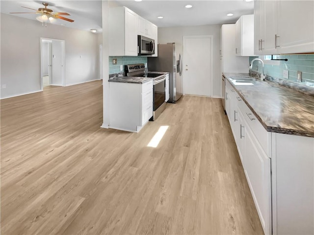 kitchen featuring sink, white cabinetry, tasteful backsplash, light wood-type flooring, and appliances with stainless steel finishes