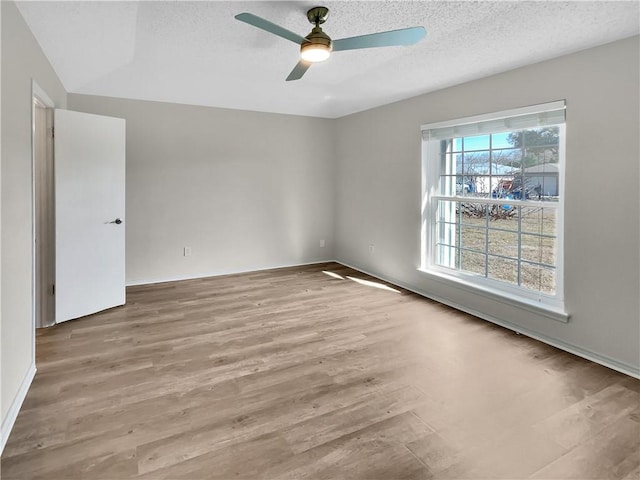 unfurnished room with ceiling fan, light hardwood / wood-style flooring, and a textured ceiling