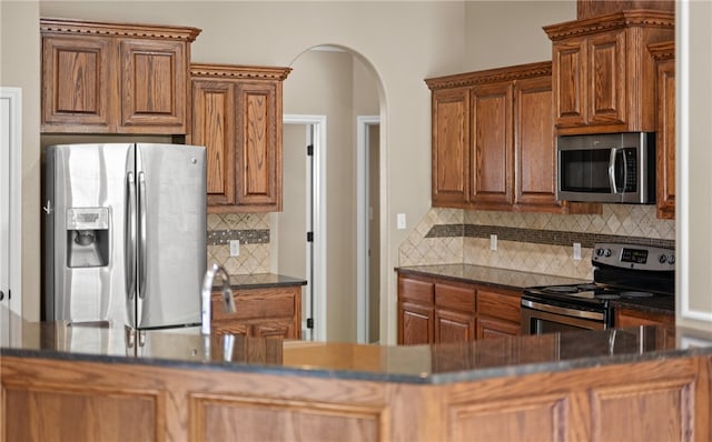 kitchen with dark stone countertops, decorative backsplash, and appliances with stainless steel finishes