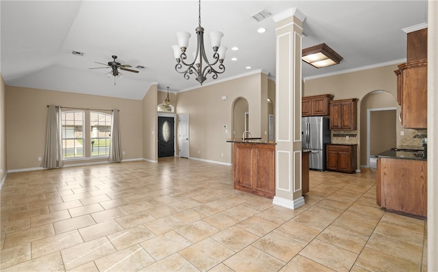 kitchen with stainless steel refrigerator, crown molding, decorative backsplash, and decorative columns