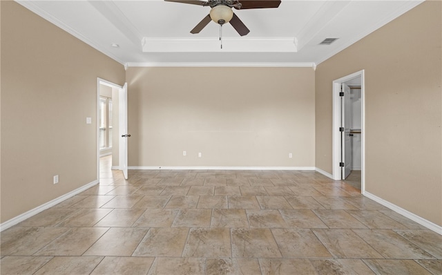 empty room with ceiling fan, a tray ceiling, and ornamental molding