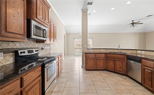 kitchen featuring stainless steel appliances, dark stone counters, sink, and backsplash