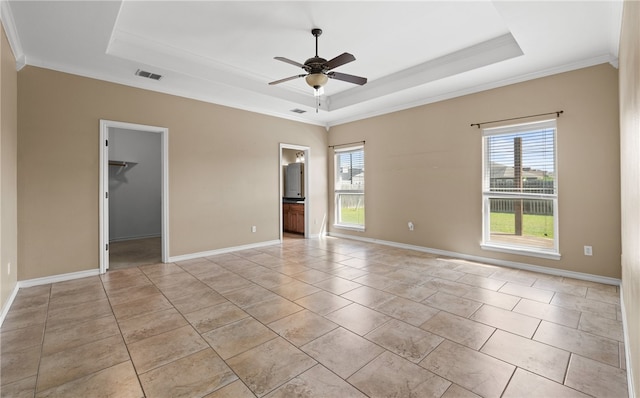 empty room featuring ceiling fan, a wealth of natural light, ornamental molding, and a raised ceiling