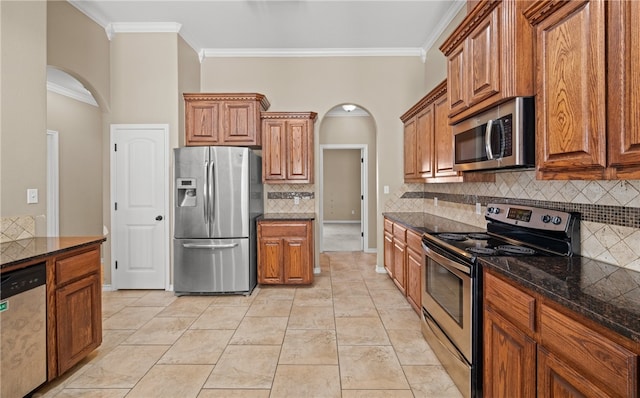 kitchen with decorative backsplash, appliances with stainless steel finishes, dark stone counters, and crown molding