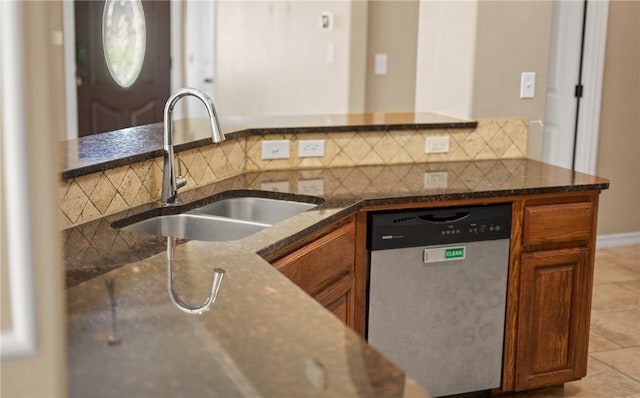 kitchen with dark stone counters, dishwasher, sink, tasteful backsplash, and light tile patterned floors