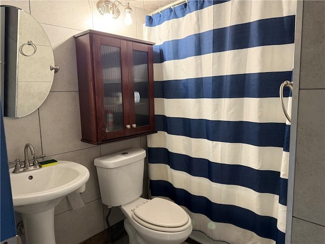 bathroom with tile walls, sink, toilet, and a shower with shower curtain