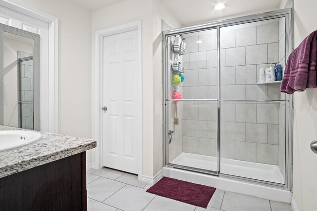 bathroom with tile patterned flooring, vanity, and a shower with shower door