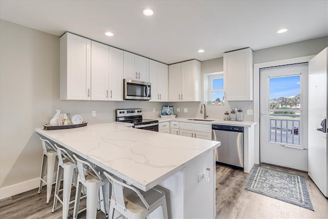 kitchen featuring kitchen peninsula, appliances with stainless steel finishes, sink, and white cabinets