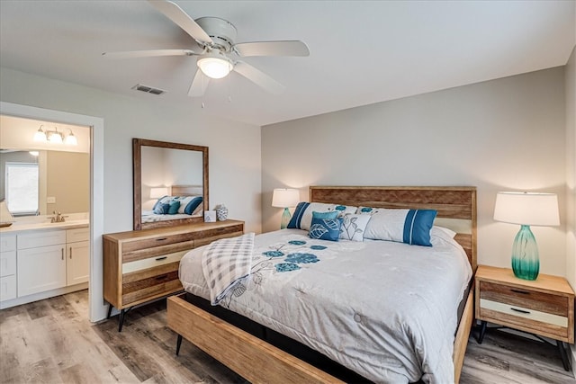 bedroom featuring light wood-type flooring, sink, ceiling fan, and ensuite bath