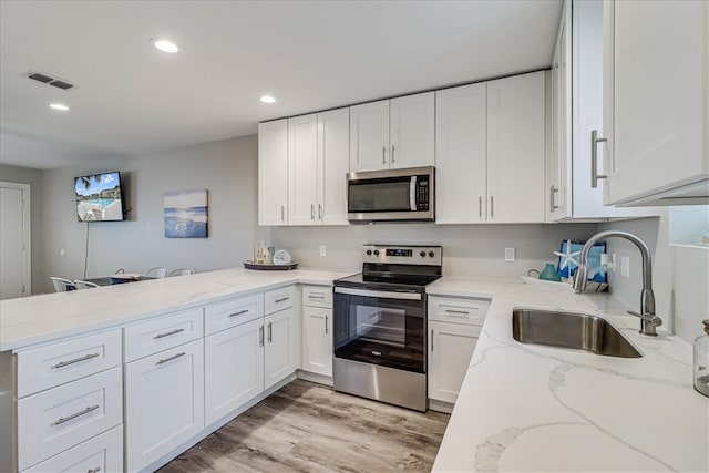 kitchen featuring white cabinetry, appliances with stainless steel finishes, sink, and light stone countertops