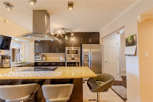 kitchen featuring stainless steel appliances, light stone counters, island range hood, dark brown cabinetry, and crown molding