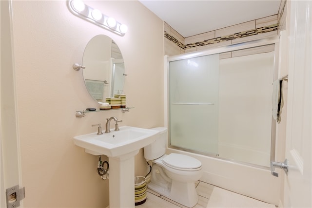 bathroom featuring tile patterned floors, combined bath / shower with glass door, and toilet