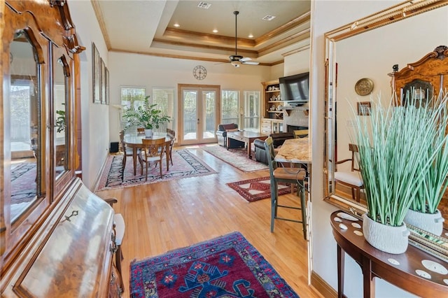 interior space featuring french doors, a raised ceiling, visible vents, ornamental molding, and wood finished floors