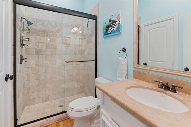 full bath with wood finished floors, a shower stall, toilet, and vanity