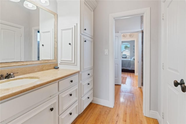 bathroom with baseboards, wood finished floors, and vanity