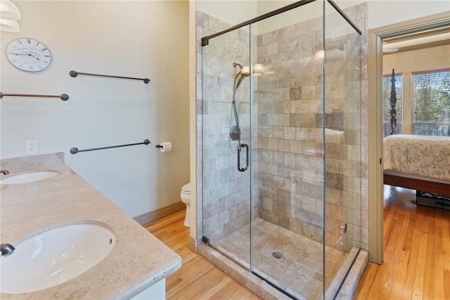 ensuite bathroom with wood finished floors, a sink, a shower stall, double vanity, and ensuite bath