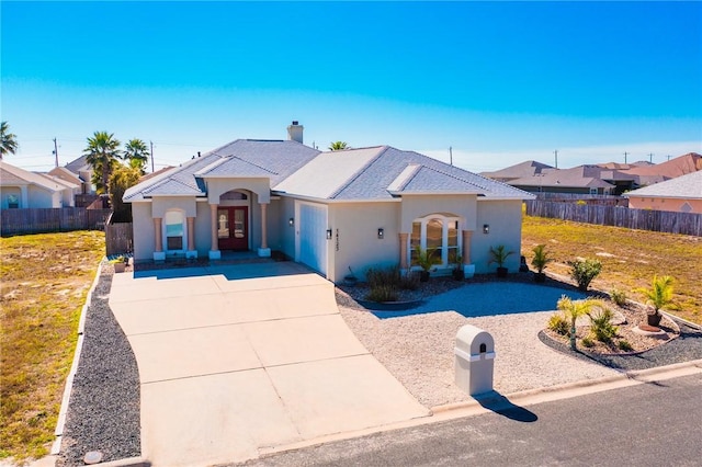 view of front of property with driveway, fence, french doors, and stucco siding