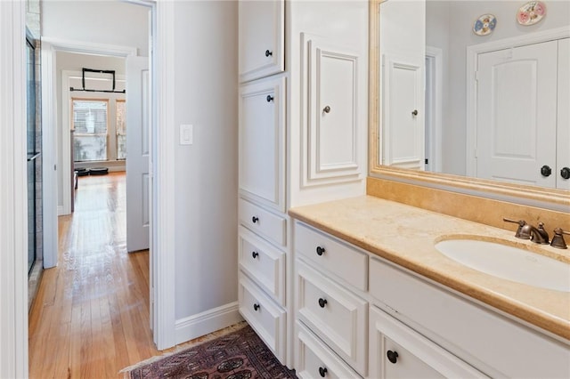 bathroom with baseboards, wood finished floors, and vanity