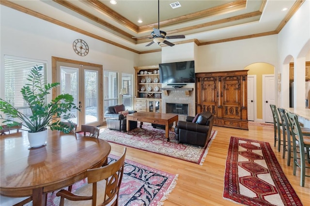 living area featuring visible vents, a raised ceiling, crown molding, and a glass covered fireplace