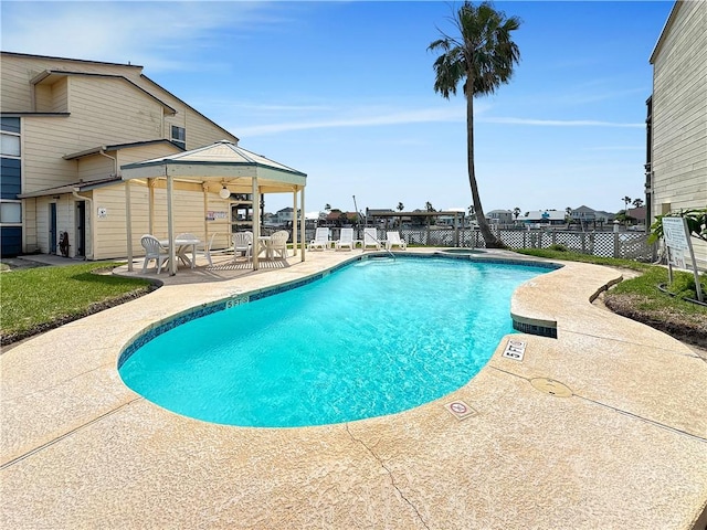 pool with a patio, fence, and a gazebo