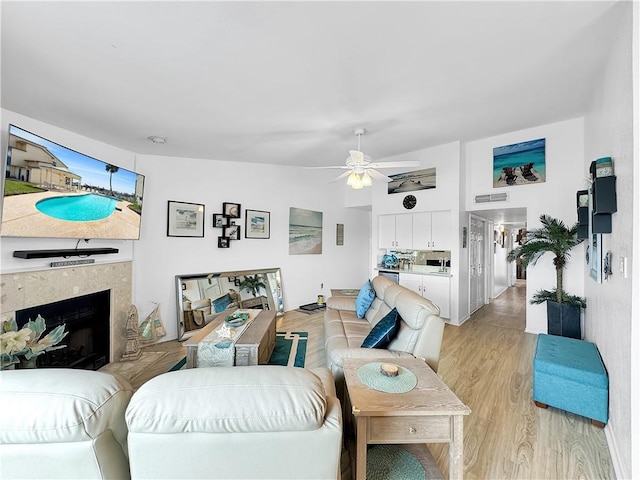 living room with a fireplace, a ceiling fan, visible vents, and light wood-type flooring