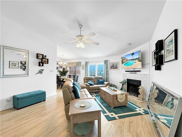 living room with baseboards, a ceiling fan, wood finished floors, and a tile fireplace