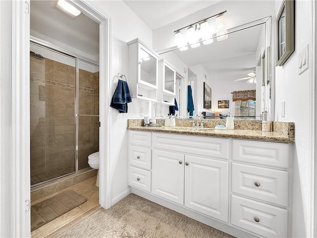 full bathroom featuring vanity, ceiling fan, toilet, and a shower stall