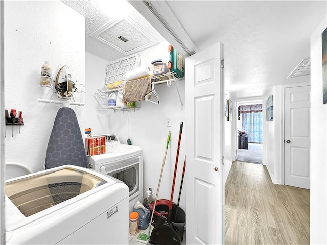 laundry area with laundry area, light wood finished floors, washing machine and dryer, and visible vents