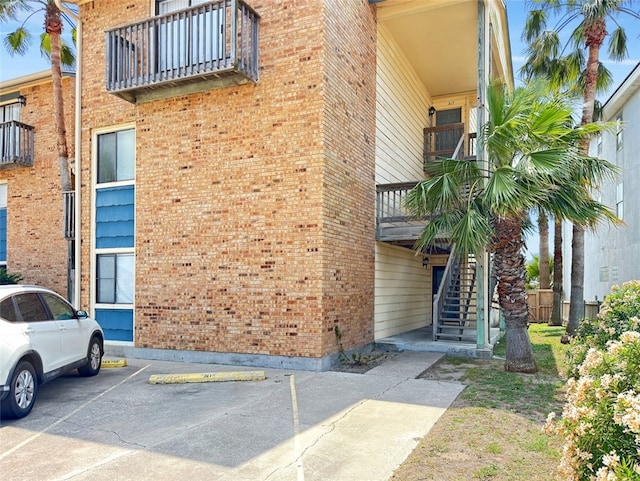 view of property with stairway and uncovered parking