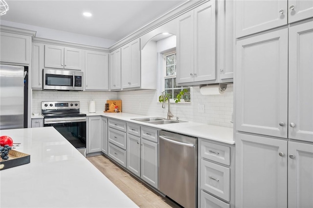 kitchen featuring sink, tasteful backsplash, gray cabinets, stainless steel appliances, and light hardwood / wood-style floors