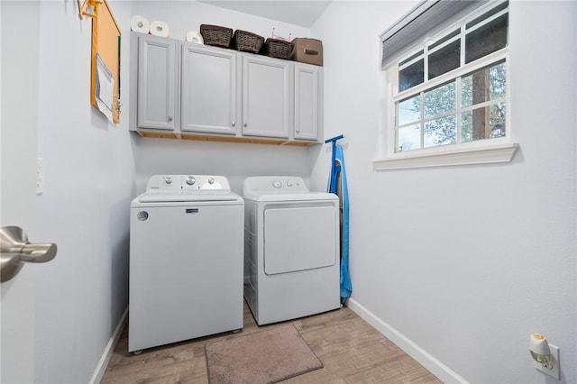 laundry area featuring cabinets, washing machine and dryer, and light wood-type flooring