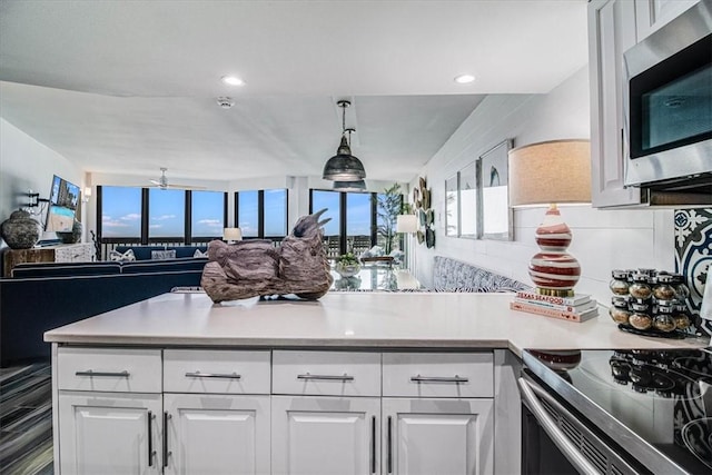 kitchen featuring appliances with stainless steel finishes, white cabinets, light countertops, and open floor plan