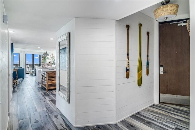 hallway featuring wood finished floors and wooden walls