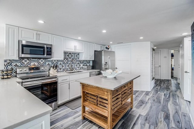 kitchen featuring tasteful backsplash, appliances with stainless steel finishes, light wood-style floors, white cabinets, and a sink