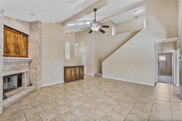 unfurnished living room with beamed ceiling, ceiling fan, high vaulted ceiling, and a brick fireplace