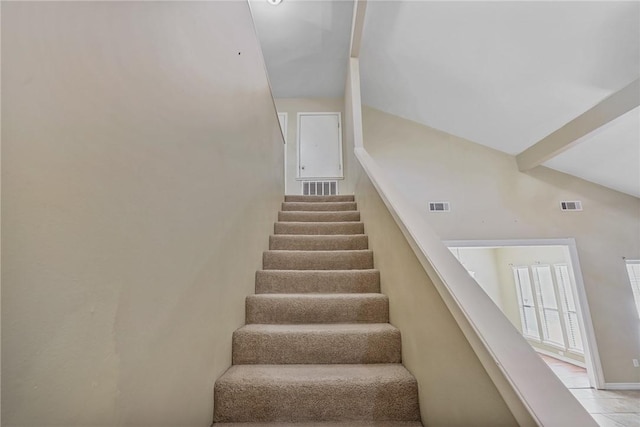 stairway featuring tile patterned flooring, beam ceiling, and high vaulted ceiling