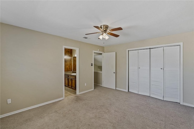 unfurnished bedroom featuring light colored carpet, ensuite bath, and ceiling fan