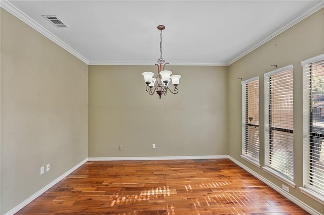 spare room featuring hardwood / wood-style floors, ornamental molding, and a notable chandelier