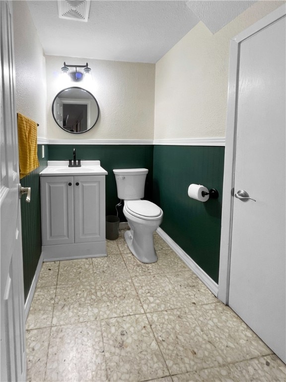 bathroom featuring toilet, vanity, a textured ceiling, and tile patterned floors