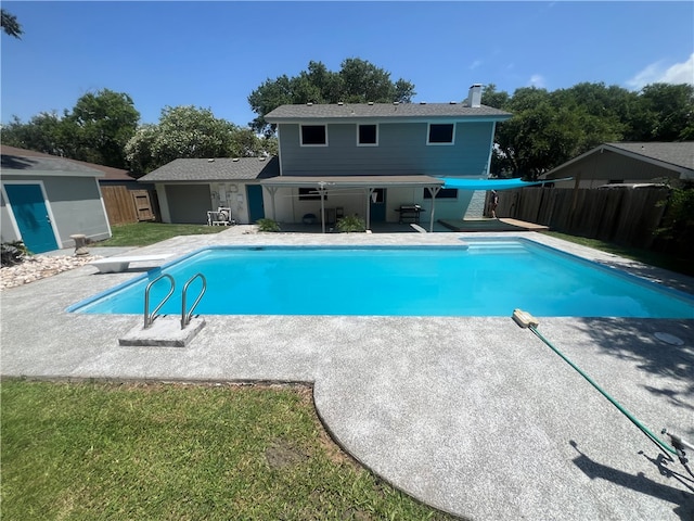 view of pool with a diving board, a lawn, and a patio area