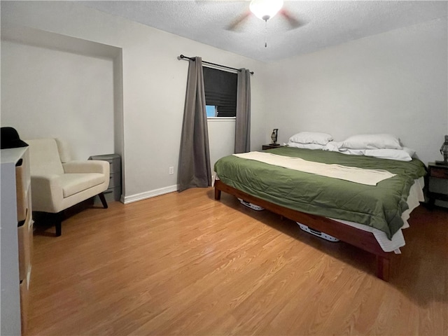 bedroom featuring hardwood / wood-style flooring, ceiling fan, and a textured ceiling