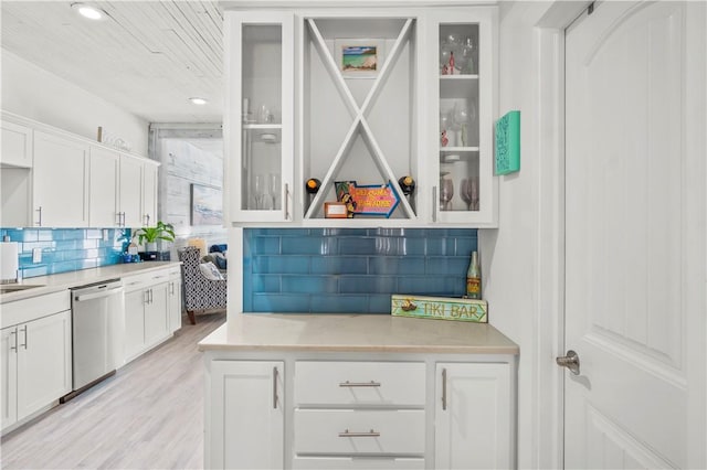 interior space with light countertops, backsplash, glass insert cabinets, white cabinetry, and dishwasher