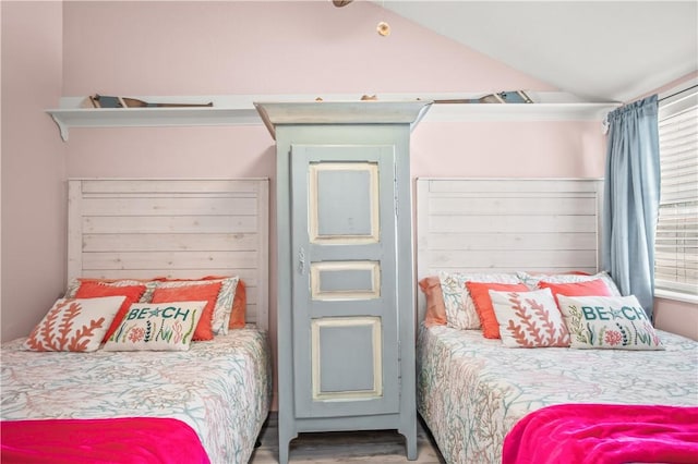 bedroom with vaulted ceiling and wood finished floors