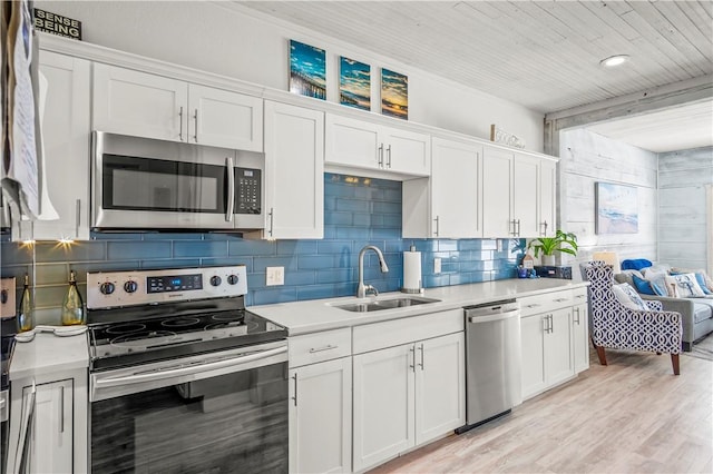 kitchen with tasteful backsplash, light countertops, appliances with stainless steel finishes, white cabinetry, and a sink