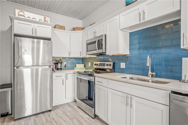 kitchen with light countertops, decorative backsplash, appliances with stainless steel finishes, white cabinetry, and a sink